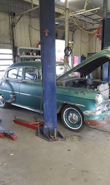 Green classic car being worked on inside a KC Auto Repair bay