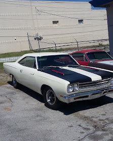 Several classic cars lined up beside KC Auto Repair